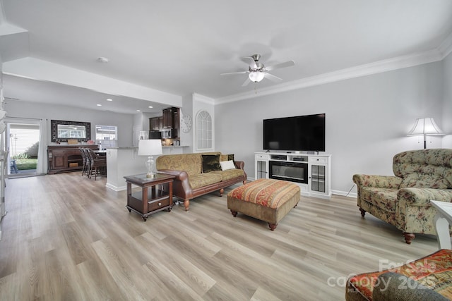 living area with light wood-style floors, ornamental molding, and ceiling fan