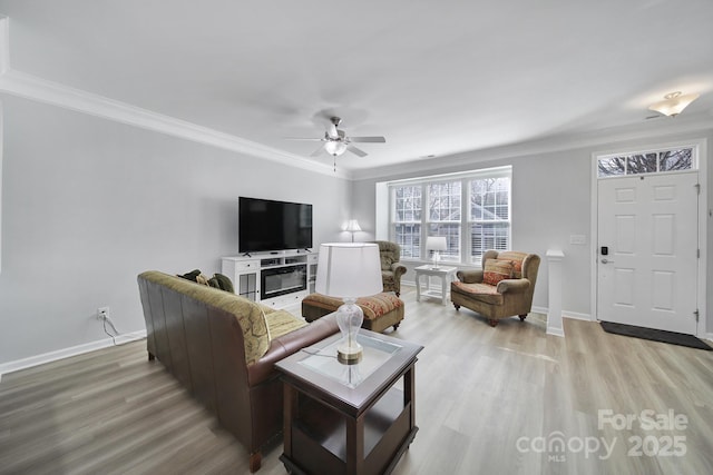 living area featuring baseboards, light wood-type flooring, and crown molding