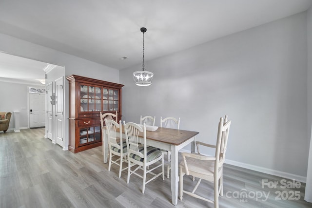 dining area with baseboards, an inviting chandelier, and light wood-style floors