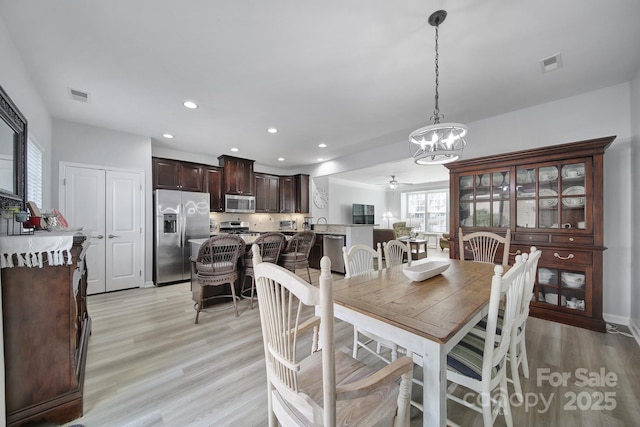 dining area with light wood-type flooring, ceiling fan with notable chandelier, visible vents, and recessed lighting