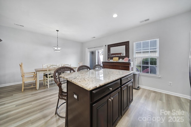 kitchen featuring light wood-style floors, visible vents, and a breakfast bar area