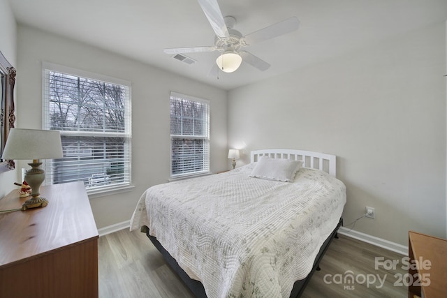 bedroom featuring wood finished floors, visible vents, and baseboards