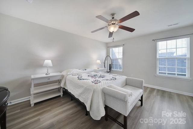 bedroom featuring a ceiling fan, visible vents, baseboards, and wood finished floors