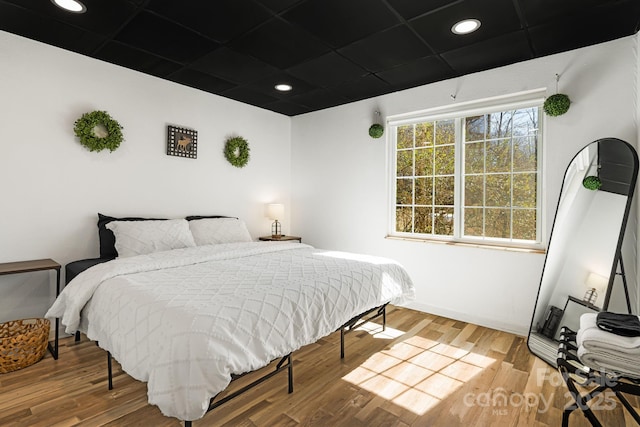 bedroom with baseboards, wood finished floors, and recessed lighting
