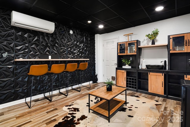 living room with a community bar, light wood-style flooring, recessed lighting, and a wall unit AC