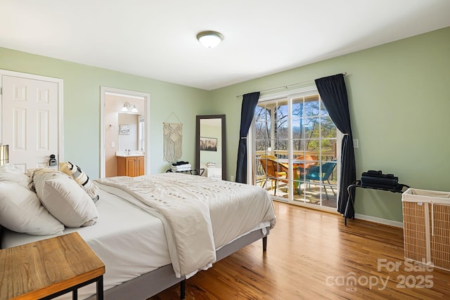 bedroom with wood finished floors, access to exterior, baseboards, and ensuite bathroom