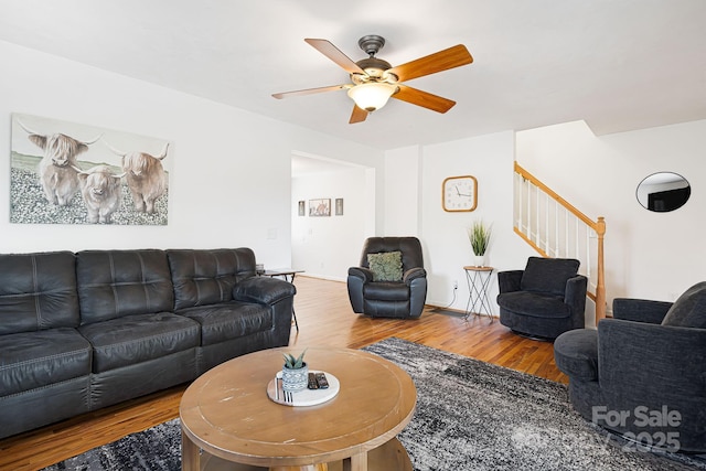 living room with a ceiling fan, wood finished floors, and stairs