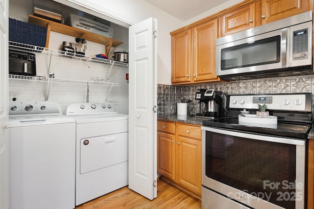 kitchen with light wood finished floors, stainless steel appliances, open shelves, washing machine and clothes dryer, and decorative backsplash
