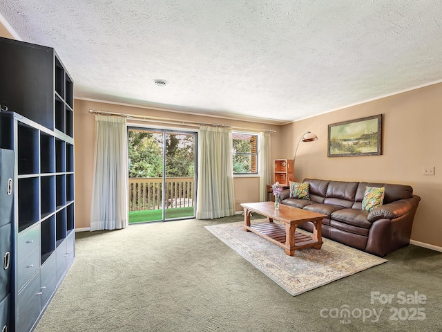 living room featuring a textured ceiling, carpet floors, ornamental molding, and visible vents