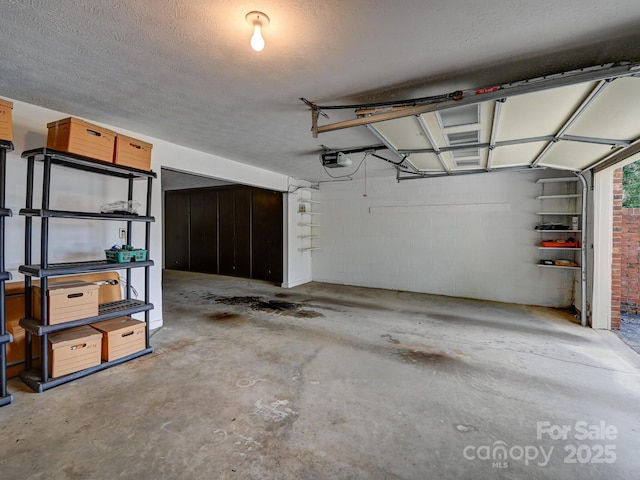 garage featuring concrete block wall and a garage door opener