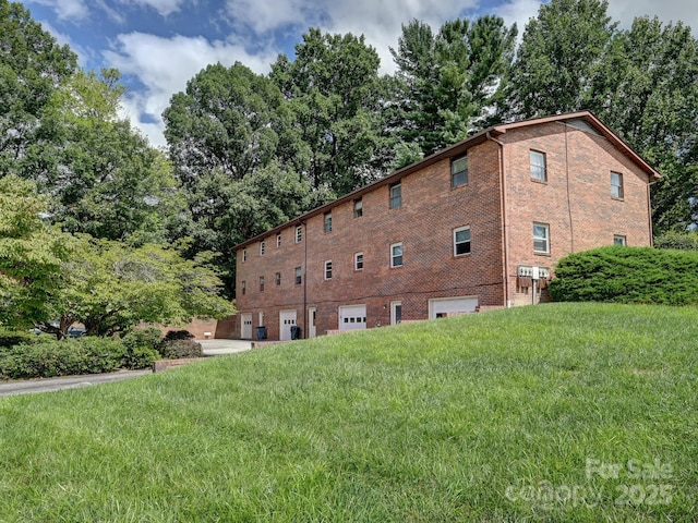 view of side of property featuring a garage, a yard, and brick siding