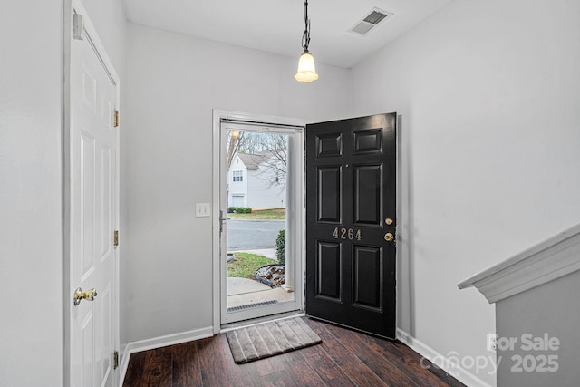 foyer entrance with visible vents, baseboards, and dark wood finished floors