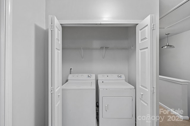 clothes washing area featuring carpet flooring, baseboards, washing machine and dryer, and laundry area