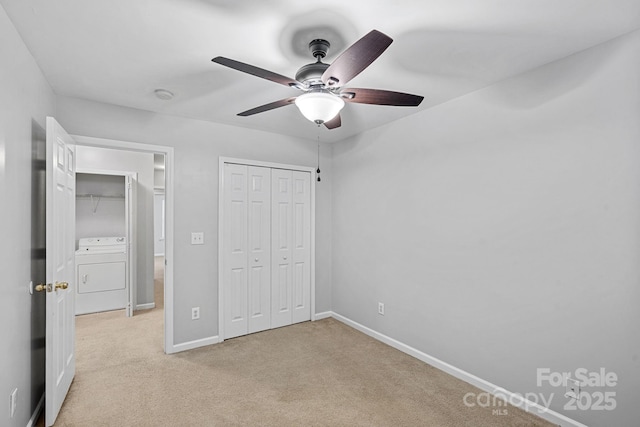 unfurnished bedroom with a closet, baseboards, light colored carpet, washer / dryer, and ceiling fan