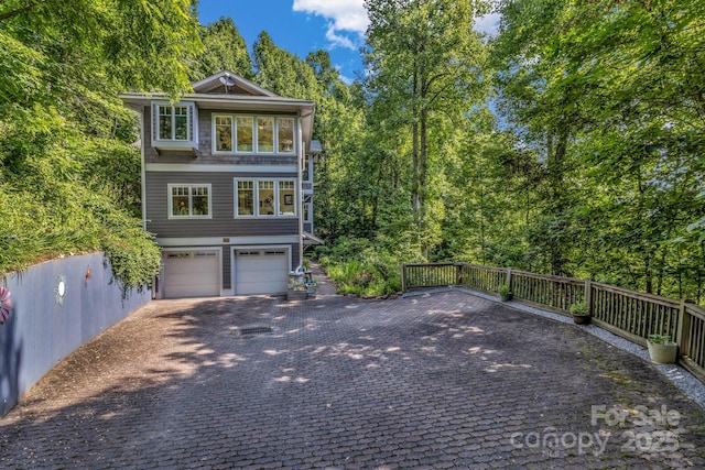 view of front of property featuring an attached garage, driveway, and fence