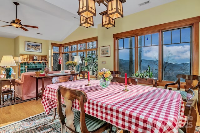 322 Crestview Dr, Black Mountain, NC 28711 - dining room featuring a tiled fireplace, lofted ceiling, wood finished floors, and visible vents