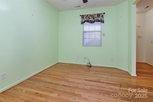 spare room featuring light wood finished floors, baseboards, visible vents, and ceiling fan