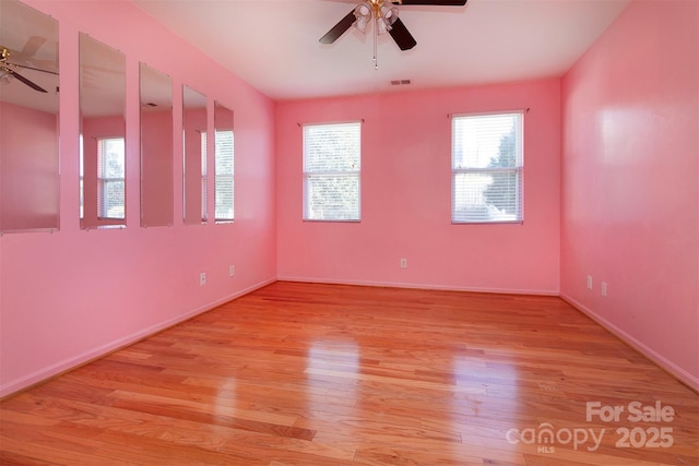 unfurnished room with a ceiling fan, light wood-type flooring, visible vents, and baseboards