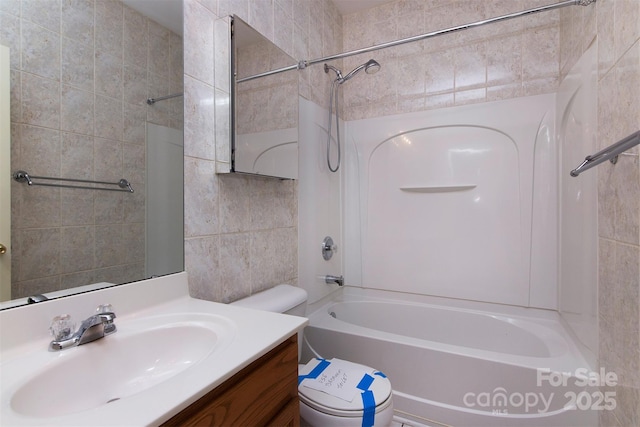 full bathroom with toilet, washtub / shower combination, tile walls, and vanity