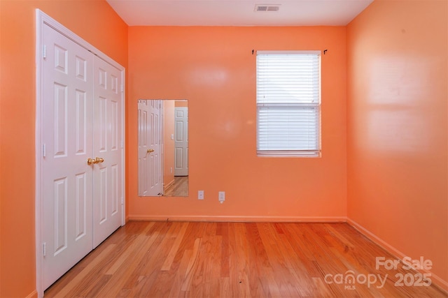 unfurnished bedroom with visible vents, light wood-style flooring, and baseboards