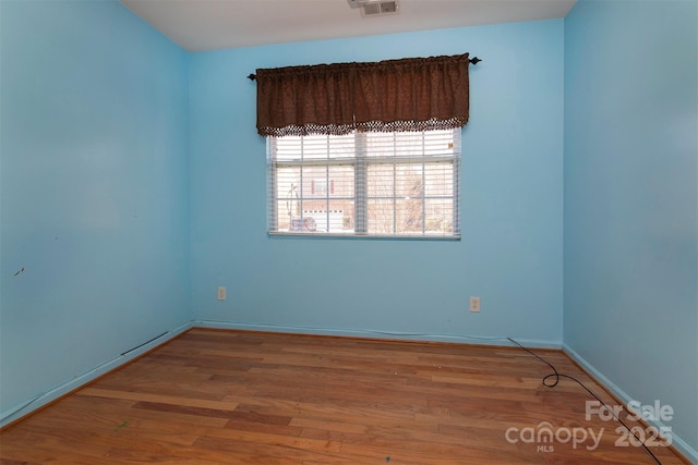 unfurnished room with visible vents, baseboards, and wood finished floors