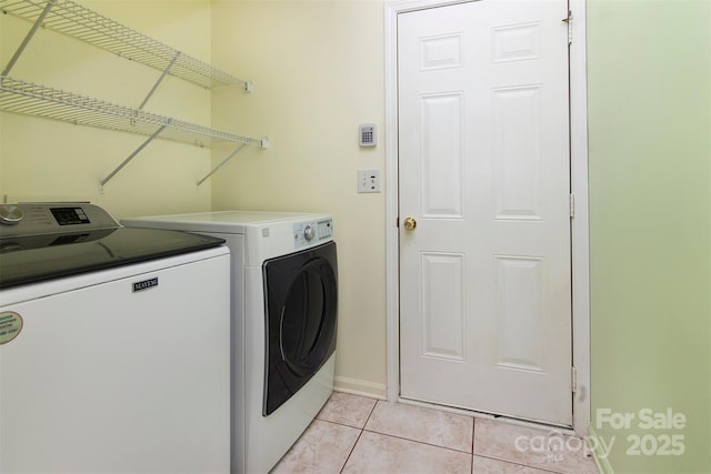 laundry area featuring laundry area, washing machine and dryer, light tile patterned floors, and baseboards