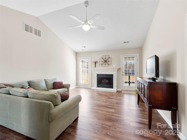 living room with a brick fireplace, visible vents, vaulted ceiling, and dark wood finished floors