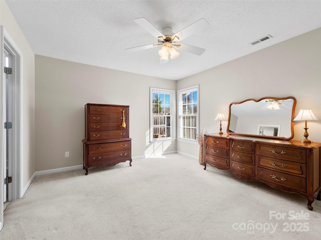 bedroom with baseboards, visible vents, a ceiling fan, light colored carpet, and a textured ceiling