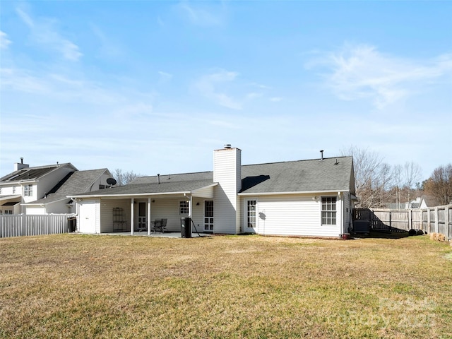 back of house featuring a patio area, a lawn, a chimney, and fence