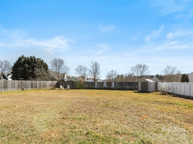 view of yard with a fenced backyard, a storage unit, and an outbuilding