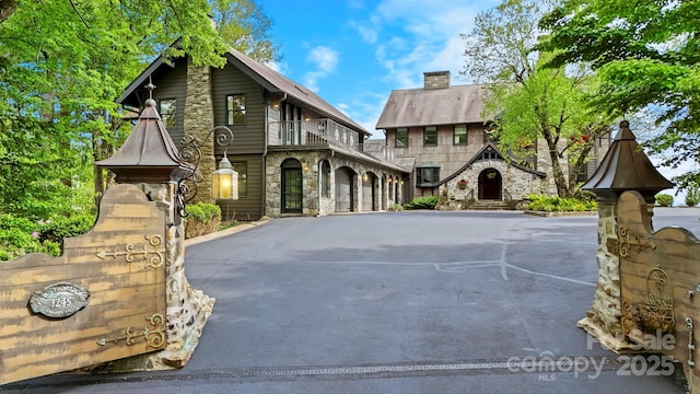 1245 Laurel Ln, Blowing Rock, NC 28605 - tudor home with stone siding, a balcony, asphalt driveway, and a chimney