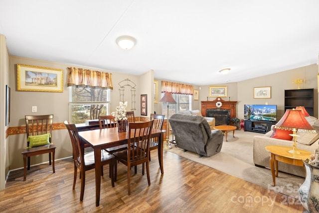 dining space featuring a glass covered fireplace, lofted ceiling, and wood finished floors