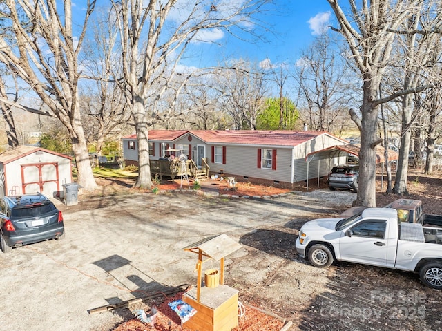 manufactured / mobile home with an outbuilding, crawl space, a shed, a carport, and driveway