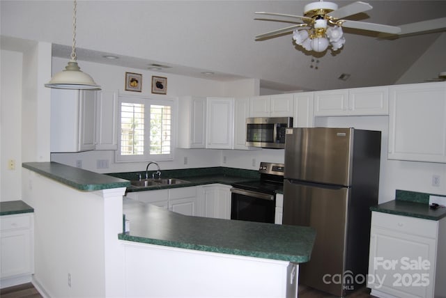 kitchen featuring stainless steel appliances, a peninsula, a sink, white cabinetry, and dark countertops