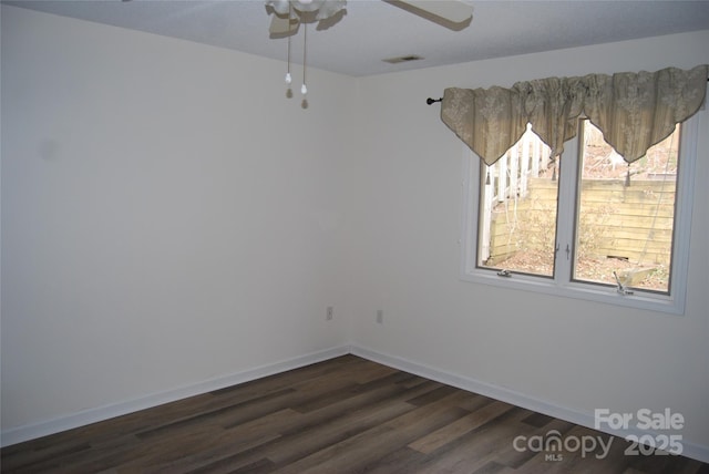 spare room with dark wood-style flooring, visible vents, ceiling fan, and baseboards