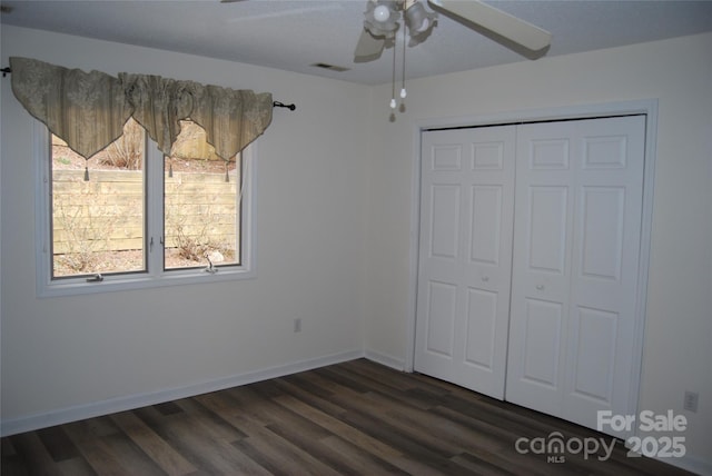 unfurnished bedroom with ceiling fan, visible vents, baseboards, a closet, and dark wood finished floors