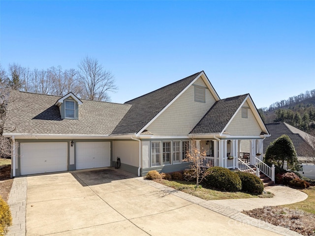 view of front of house featuring an attached garage, covered porch, a shingled roof, and concrete driveway