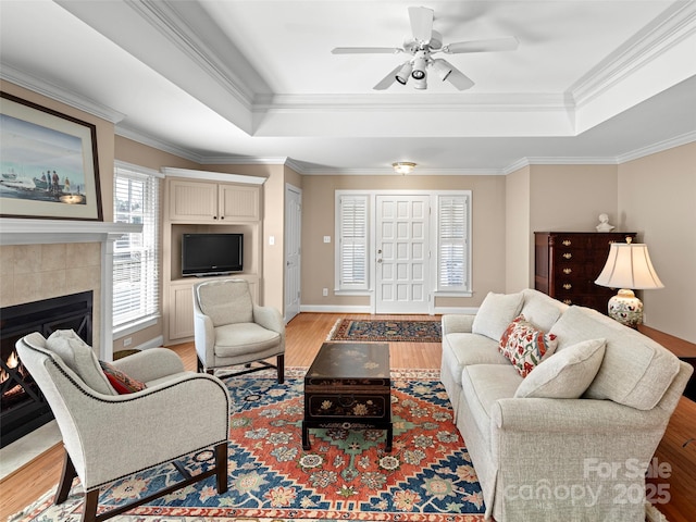 living room featuring ornamental molding, a raised ceiling, and light wood finished floors