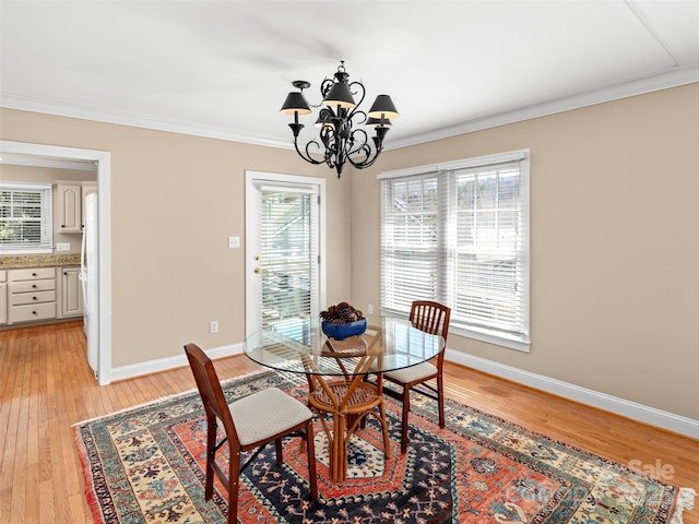 dining space with light wood finished floors, ornamental molding, a chandelier, and baseboards