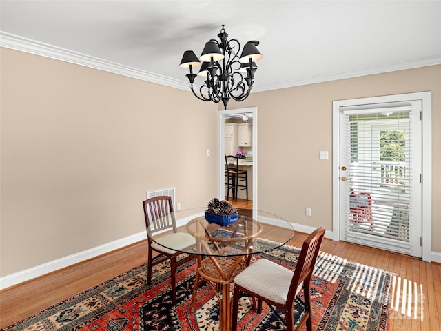 dining space featuring baseboards, crown molding, and light wood finished floors