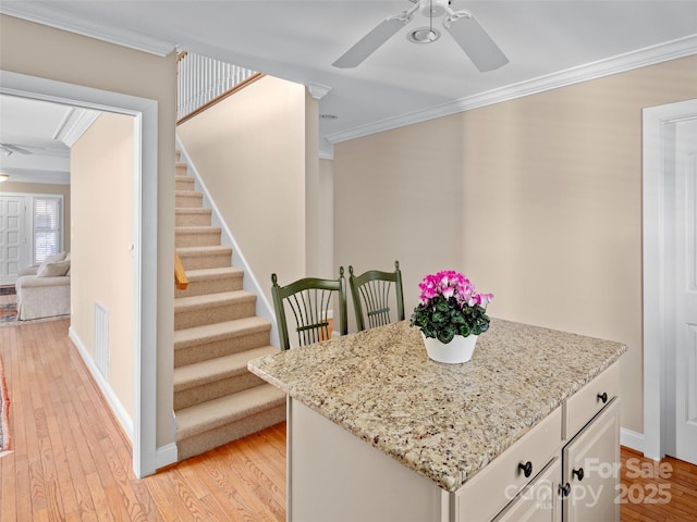 interior space featuring light wood-type flooring, visible vents, ornamental molding, and a ceiling fan