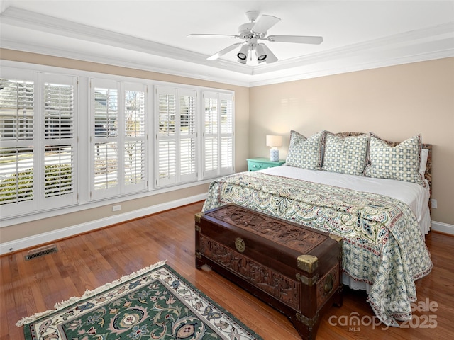 bedroom with baseboards, wood finished floors, visible vents, and crown molding