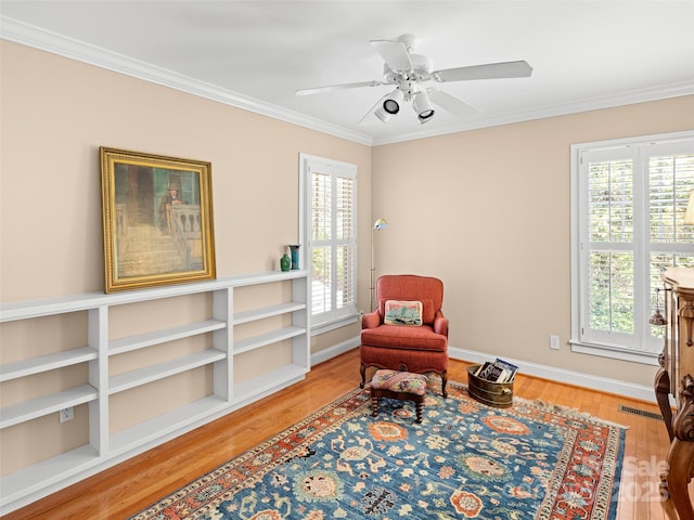 sitting room with a healthy amount of sunlight, crown molding, baseboards, and wood finished floors