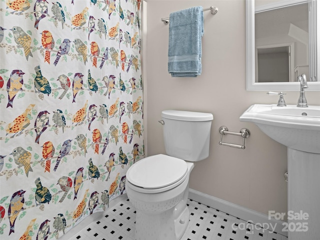 bathroom featuring baseboards, a shower with shower curtain, and toilet