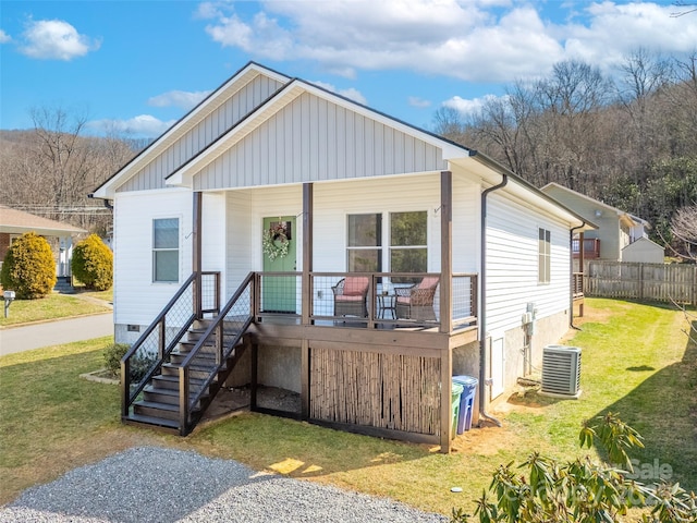 view of front of house with central AC unit, covered porch, fence, stairway, and a front lawn