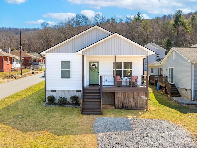 view of front facade featuring stairs, crawl space, covered porch, and a front yard