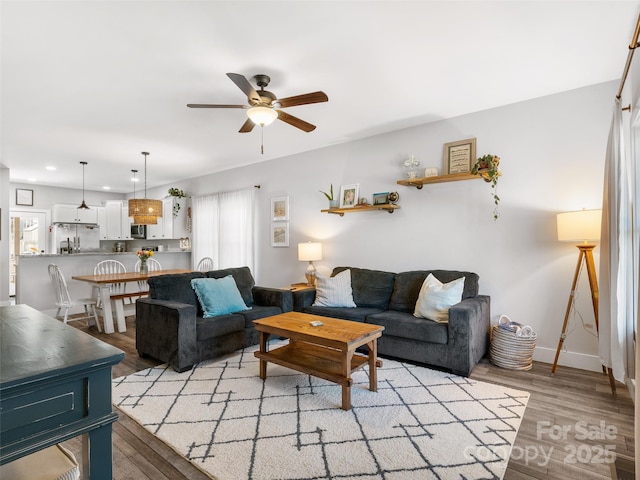 living area featuring ceiling fan, recessed lighting, baseboards, and light wood-style floors