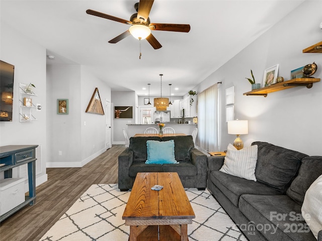 living room featuring light wood-type flooring, baseboards, a ceiling fan, and recessed lighting