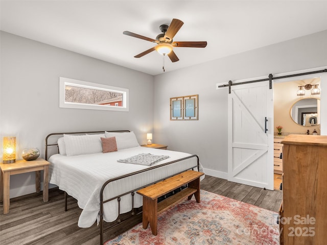 bedroom featuring a ceiling fan, wood finished floors, baseboards, and a barn door