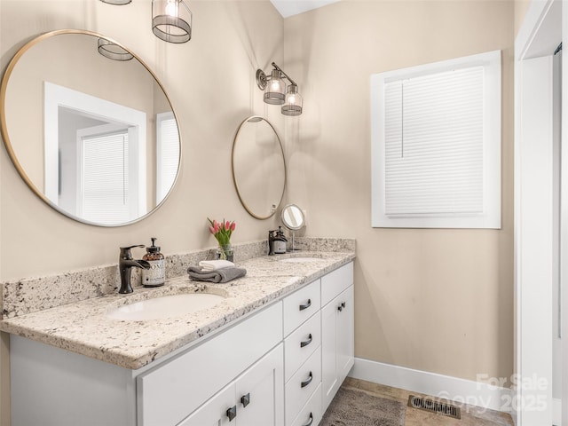 bathroom with visible vents, a sink, baseboards, and double vanity